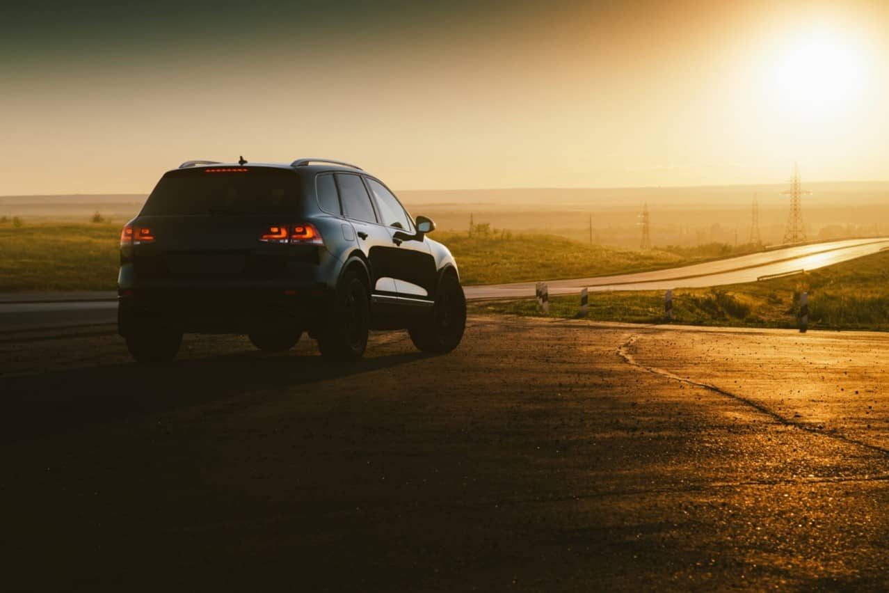 A car parked in a serene countryside carpark at dusk. 