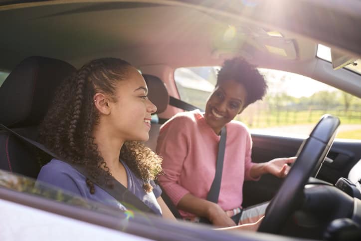 Teenage Girl In Car Having Driving Lesson From Female Instructor Or Parent