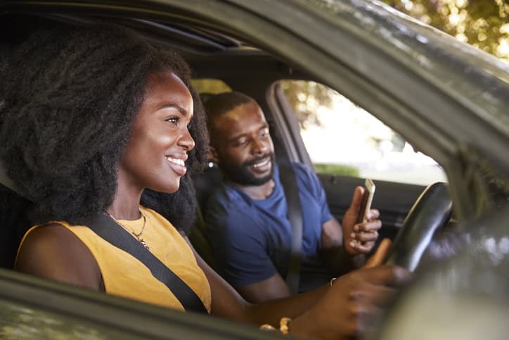 A young black man checks smartphone during a road trip