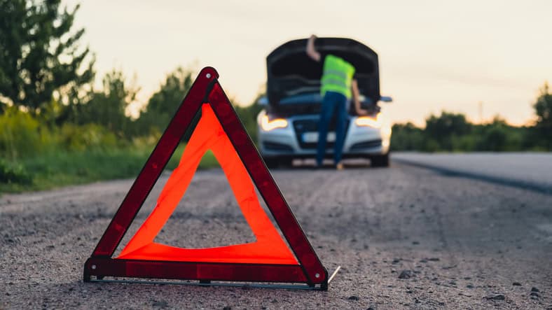 Man driver installing red triangle stop sign on road