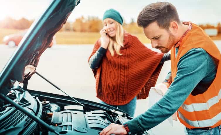 A man and a woman trying to fix a broken car
