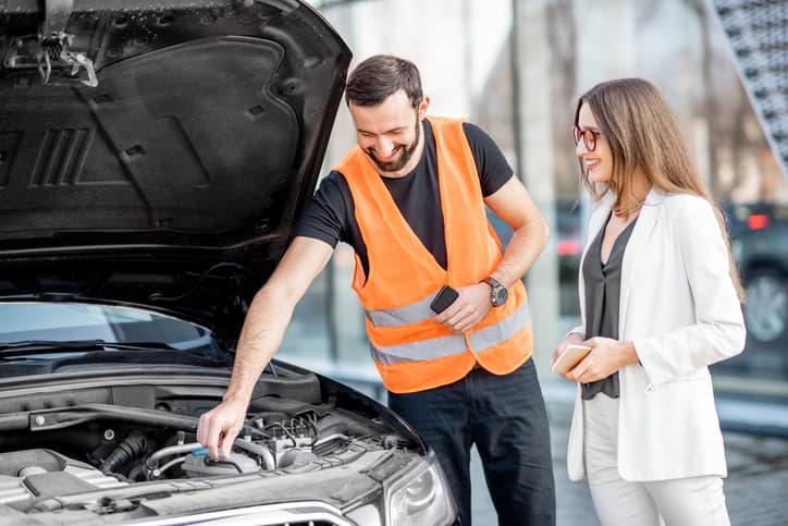 Service worker with businesswoman and car with open bonnet