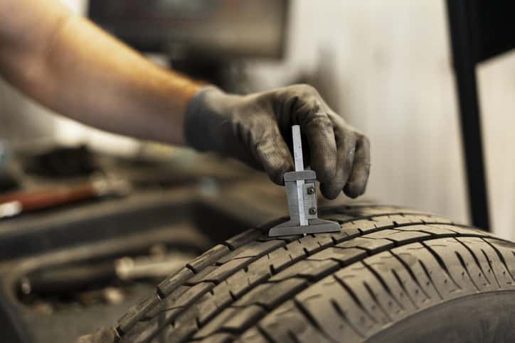 Mechanic measuring tyre tread depth using caliper