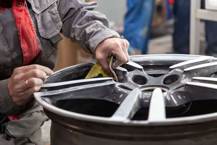 Repair man is working on preparing the surface of the aluminum wheel of the car